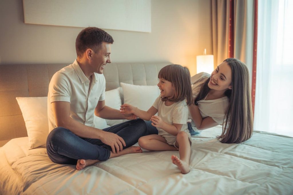 Happy family in hotel room, kids playing, bright and cozy environment