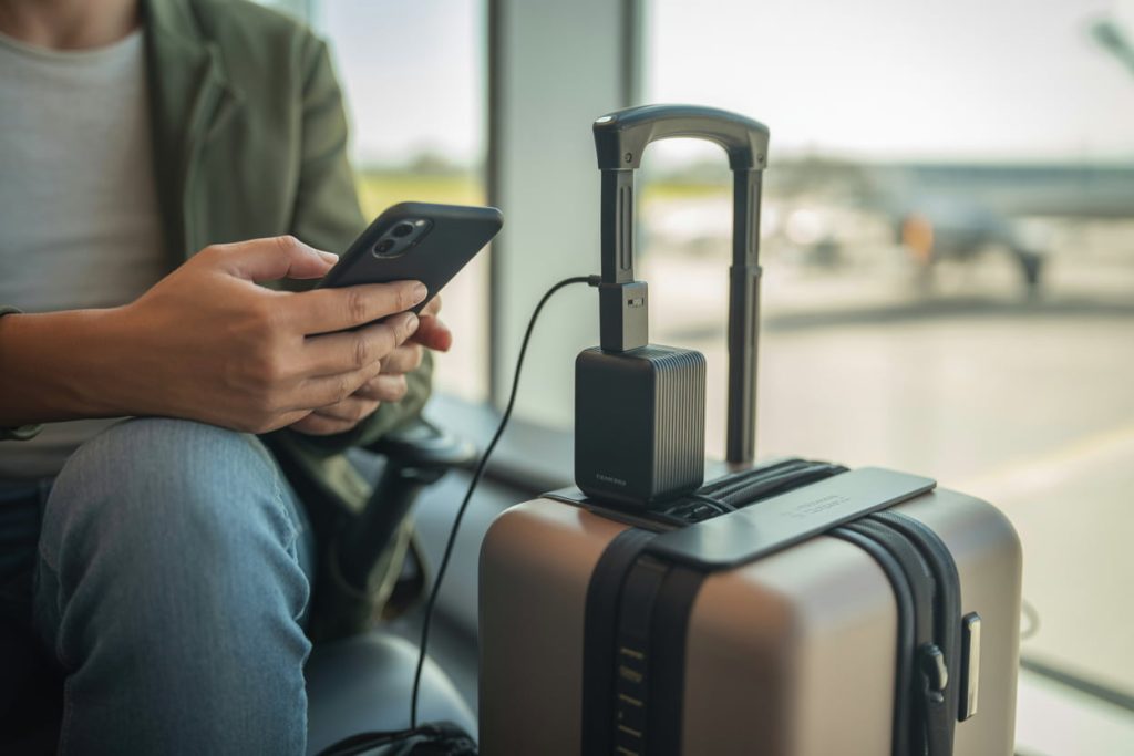 Traveler charging a phone at an airport using a universal travel adapter, natural lighting, candid travel photo